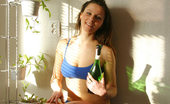 Nubiles Helen SUcking On A Wine Bottle Helen Is In A Blue Bikini And Standing Next To Plants
